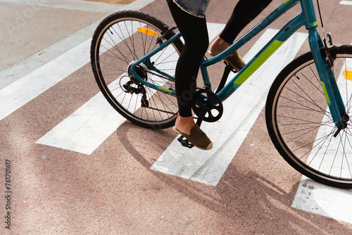 Close-up view of a woman's feet as she rides a bicycle across a pedestrian crossing