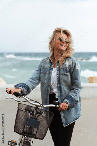Woman in a denim jacket enjoys a solo bike ride along a seaside promenade