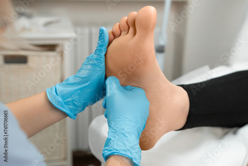 Masseur in rubber gloves is giving a foot massage to a woman. 