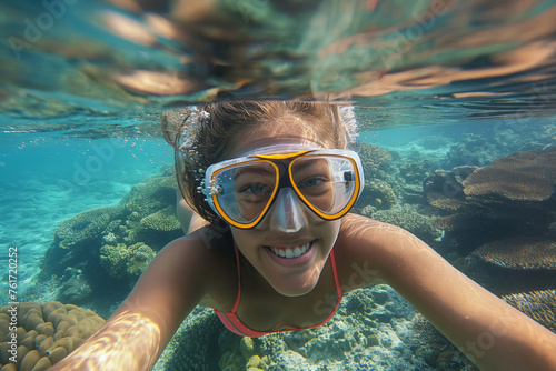 Cheerful young woman enjoying snorkeling over a vibrant coral reef, with a selfie point of view