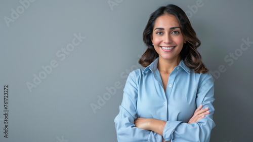 Happy young smiling confident professional business woman wearing blue shirt, happy pretty female executive looking at camera, standing arms crossed isolated at gray background, portrait.