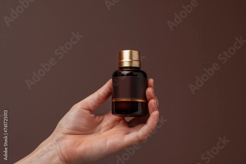 Close-up of hand holding luxury elegant skincare product bottle on a rich chocolate brown isolated solid background, conveying warmth and luxury,