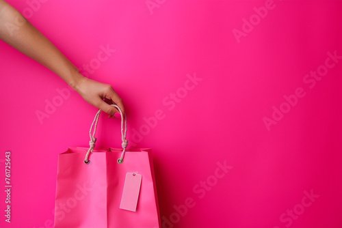 Close-up shot of hand gripping shopping bag on a bright fuchsia isolated solid background, highlighting the joy and vibrancy of shopping,