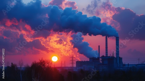 smoke billowing from the chimneys of manufacturing plant against the backdrop of a fiery sunset 