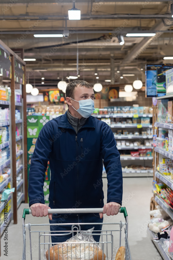 A man with a shopping basket selects goods in a supermarket. Retail trade. Quarantine