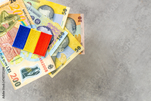 Romania money, gray background, copy space, various Romanian leu banknotes and beautiful embroidered country flag
