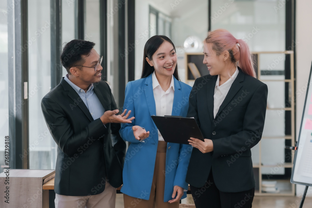 Three people in business attire are smiling and talking to each other