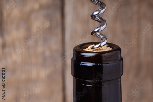 Close-up view of corkscrew in wine bottle cork to open it. Macro photography concept of uncorking bottle of wine. photo