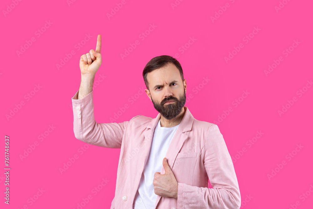 A man dressed in a pink jacket indicates the direction on a pink isolated background. A man dressed in a pink jacket indicates the direction on a pink isolated background.