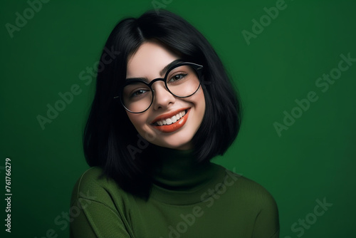 Smiling young woman with glasses on a green background photo