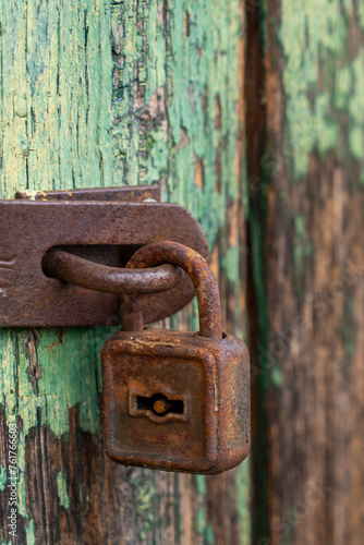 Old rusty padlock with shabby green painted wooden surface background texture