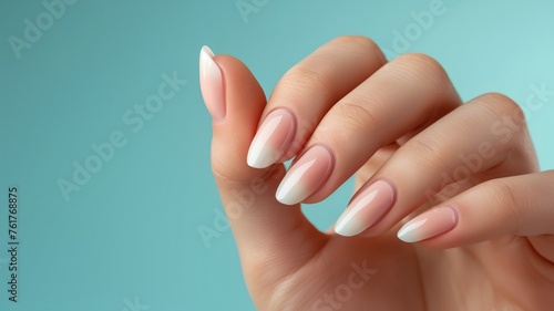 Close-up of a hand showcasing trendy pastel nail art against a soft blue background