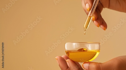 Dropper dispensing golden oil into a dish, suggestive of skincare and beauty treatments photo