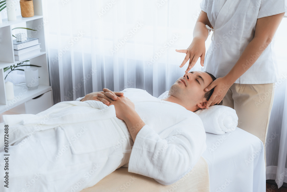 Caucasian man enjoying relaxing anti-stress head massage and pampering facial beauty skin recreation leisure in dayspa modern light ambient at luxury resort or hotel spa salon. Quiescent