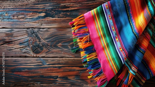 A bright, multicolored Mexican serape draped over a textured wooden background, rich in pattern photo