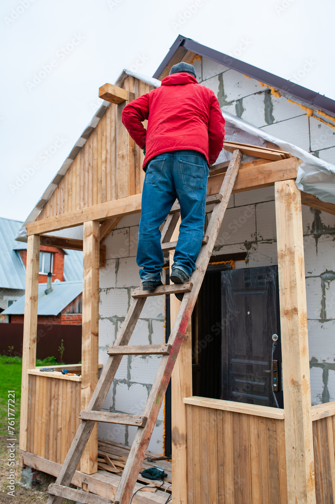 Roofer construction worker working on a roof structure at a house construction site Roofer construction worker working on a roof structure at a house construction site