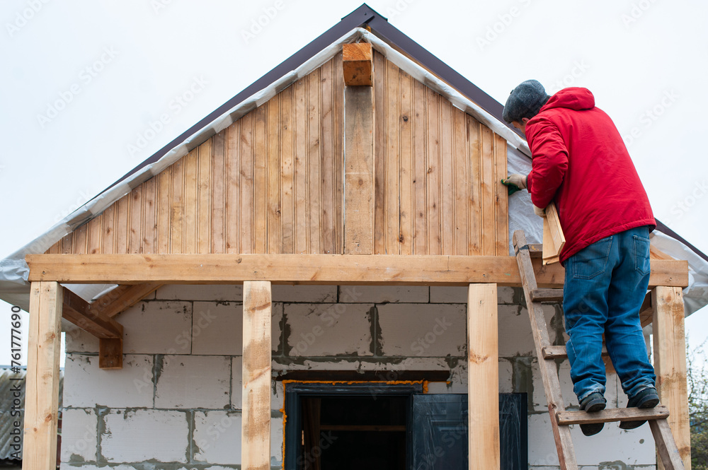 Roofer construction worker working on a roof structure at a house construction site Roofer construction worker working on a roof structure at a house construction site