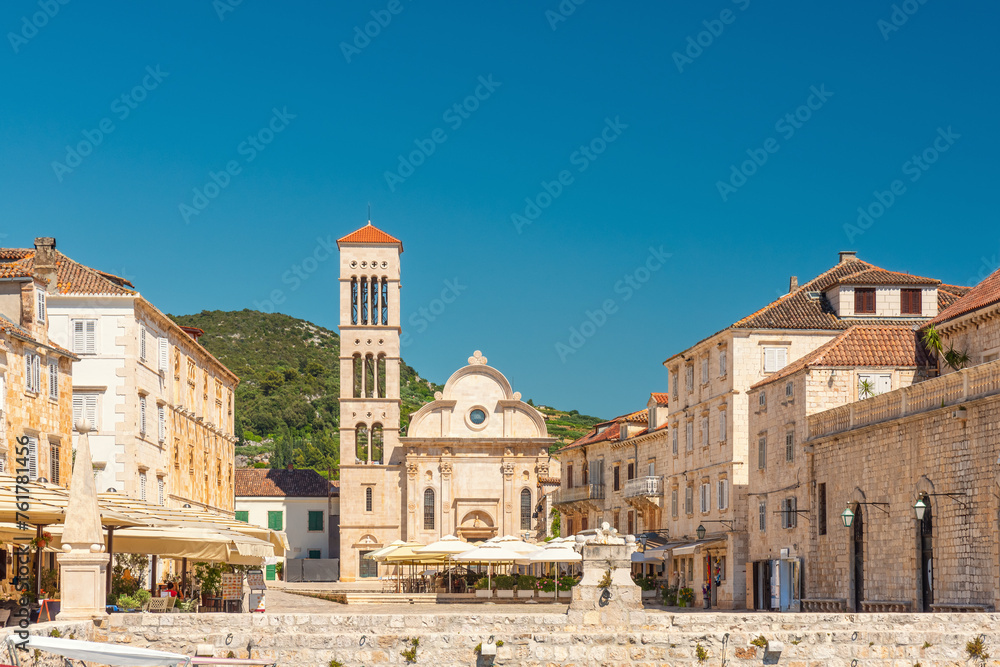 Main square Pjaca in old medieval town Hvar with Cathedral of St. Stephen, outdoors restaurants and side walk cafe on sunny day, Dalmatia, Croatia. Popular travel and tourist destination