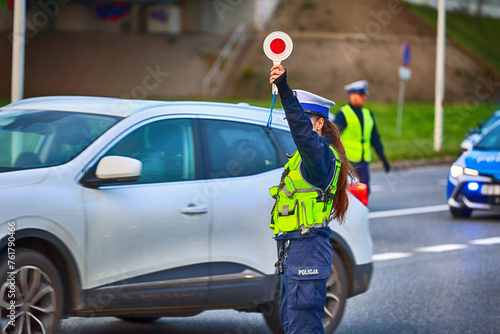 Policjantka ruchu drogowego z lizakiem podczas zatrzymania pojazdów na drodze z tarczą do zatrzymywania. 