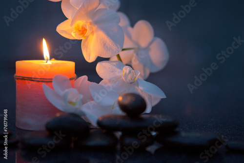 Spa background with white orchid , candle and zen black stones on gray.