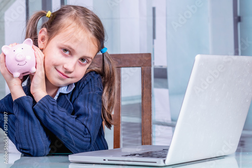 Young beautiful girl with piggy bank counting her budget pay online on laptop from home. She make payment on internet on computer.