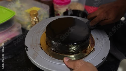 Unrecognizable man cook turns dish, removes excess chocolate glaze from cake. Making sweet desserts. Bakery. Cooking courses. Own production. Cakes to order. Small business. Handmade work.
