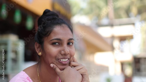 Smiling beautiful young Indian ethnic woman looking at camera posing in street during day.