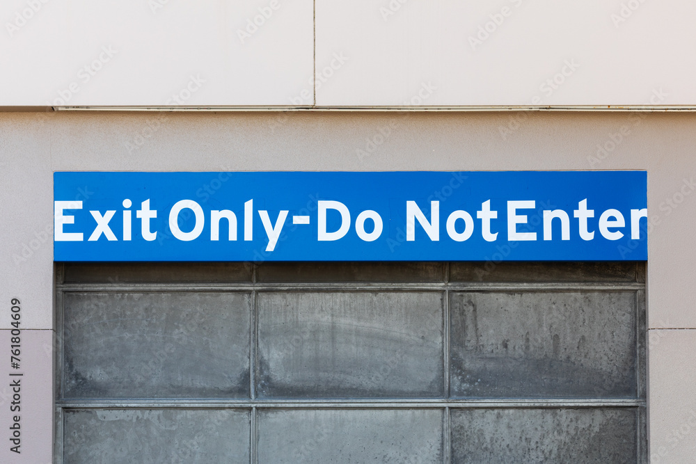Do not enter exit only warning sing on a wall near metallic garage parking door gate Do not enter exit only warning sing on a wall near metallic garage parking door gate