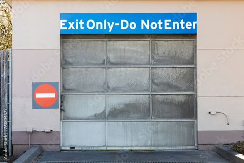 Fototapeta Naklejka Na Ścianę i Meble -  Do not enter exit only warning sing on a wall near metallic garage parking door gate