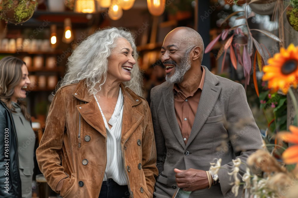 A senior man and woman of different ethnicities share and enjoy their time together, in an open-air market surrounded by flowers, romantic relationships, and mature, inclusive love.