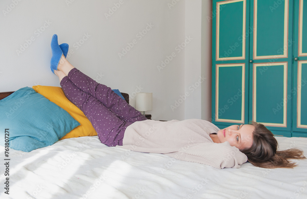 Calm woman lying down on the bed with legs up and relaxing at home Calm woman lying down on the bed with legs up and relaxing at home