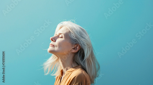 portrait of a long white hair elderly woman closing her eyes isolated blue background photo