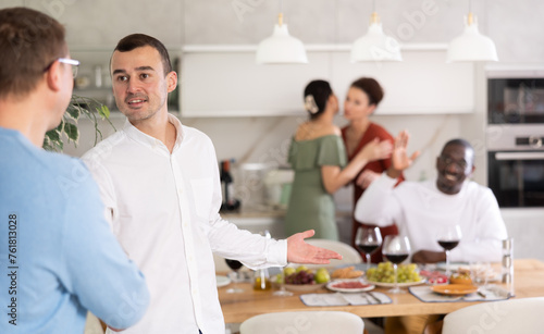 Happy middle-aged man welcoming his guest during small gathering with close friends at home photo