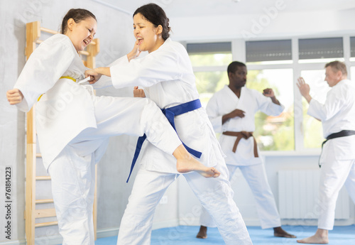 In gym, cosmopolite athletes work in pairs and learn to use classic karate techniques to repel an opponents blow, hone melee skills, strengthen spirit. Sport as lifestyle. photo