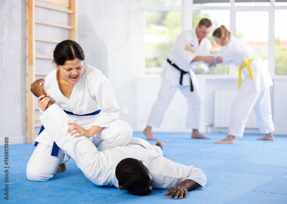 Multinational athletes train technique of performing effective protection with wring hands during training in judo techniques.