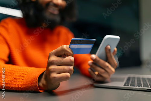 Man smiling holding credit card and phone