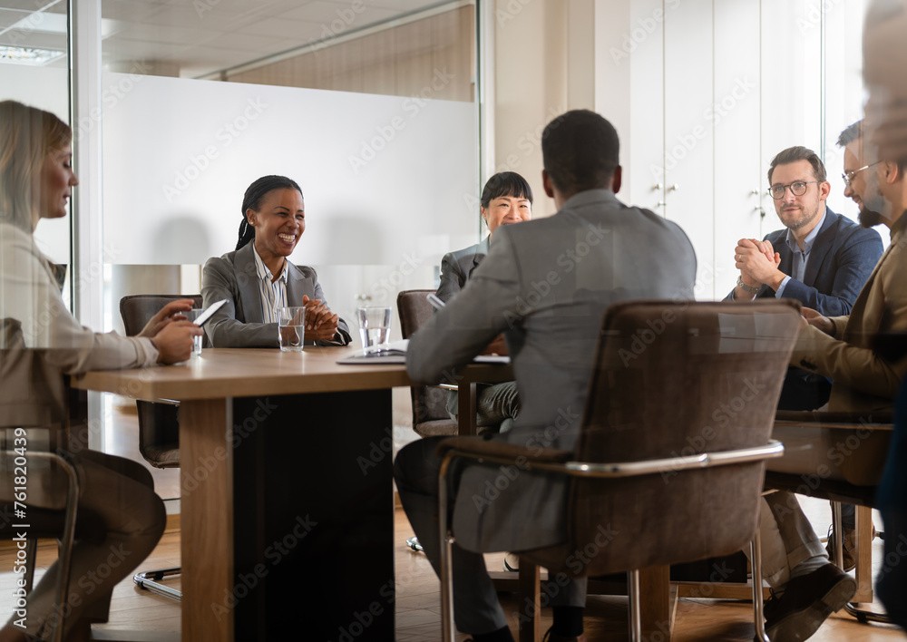 A diverse group of multi-ethnic businesswomen and businessmen sit in a corporate office and have a meeting. Cheerful business persons talking on a meeting A diverse group of multi-ethnic businesswomen and businessmen sit in a corporate office and have a meeting. Cheerful business persons talking on a meeting