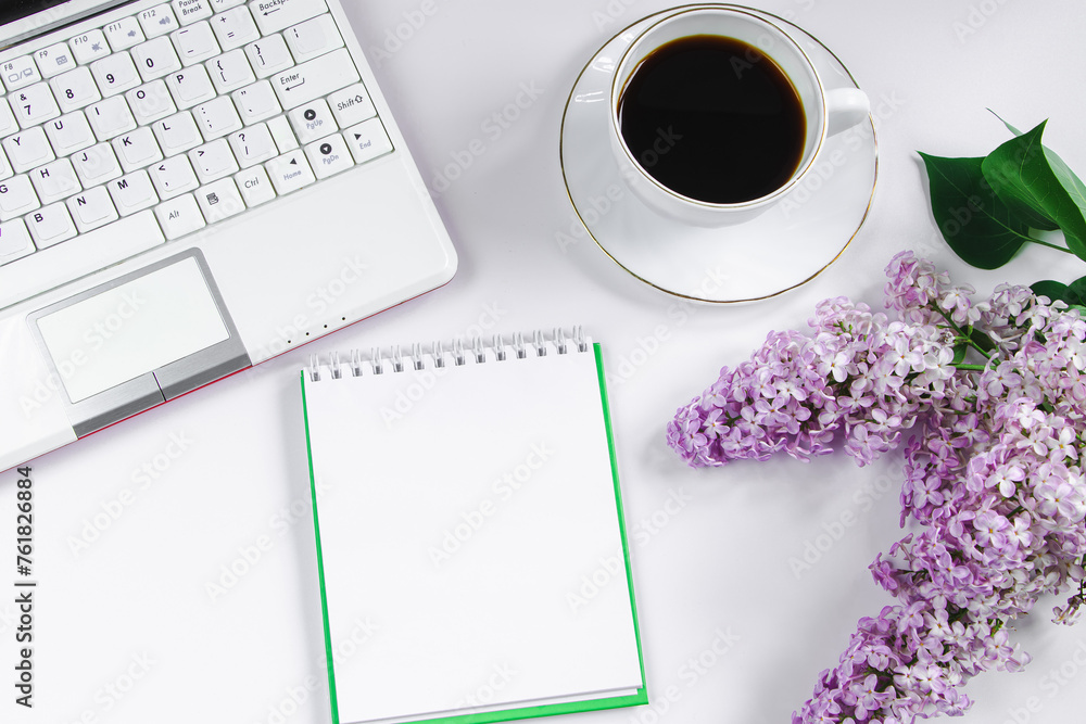 Spring flatlay. Notepad, laptop, lilac flowers and cup of coffee on light background. Spring flatlay. Notepad, laptop, lilac flowers and cup of coffee on light background.