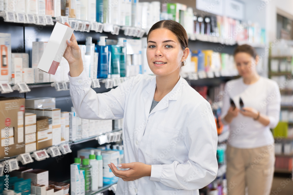 Woman pharmacist puts goods on the shelves - healing cosmetics and body care