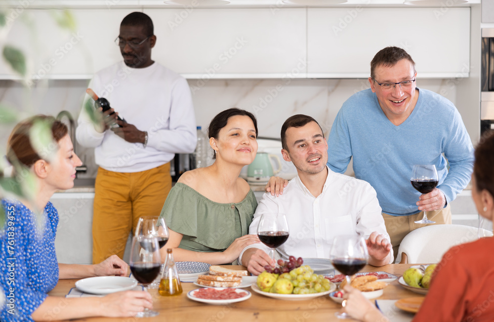 Happy companions congregated around a festive table, participating in animated discussions and enjoying the delights of red wine