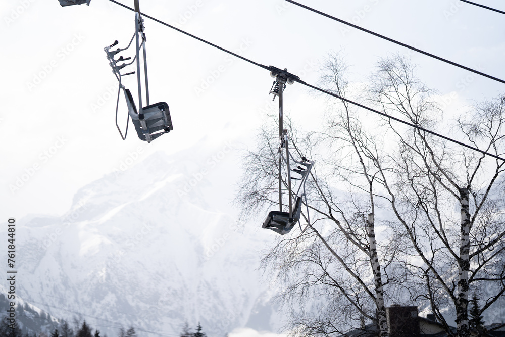 Ski lift chairs against snowy mountains and trees