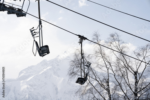 Ski lift chairs against snowy mountains and trees