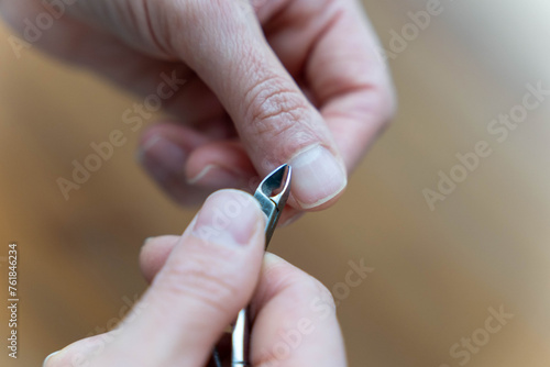 women s hands do manicures by trimming cuticles with nail clippers
