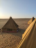 Campement de tente en plein milieu d'un désert, soleil couchant, reflet de lumière, camping entre amis, splot indien incourtounable, plaisir détente touristique, que du sable à l'horizon 