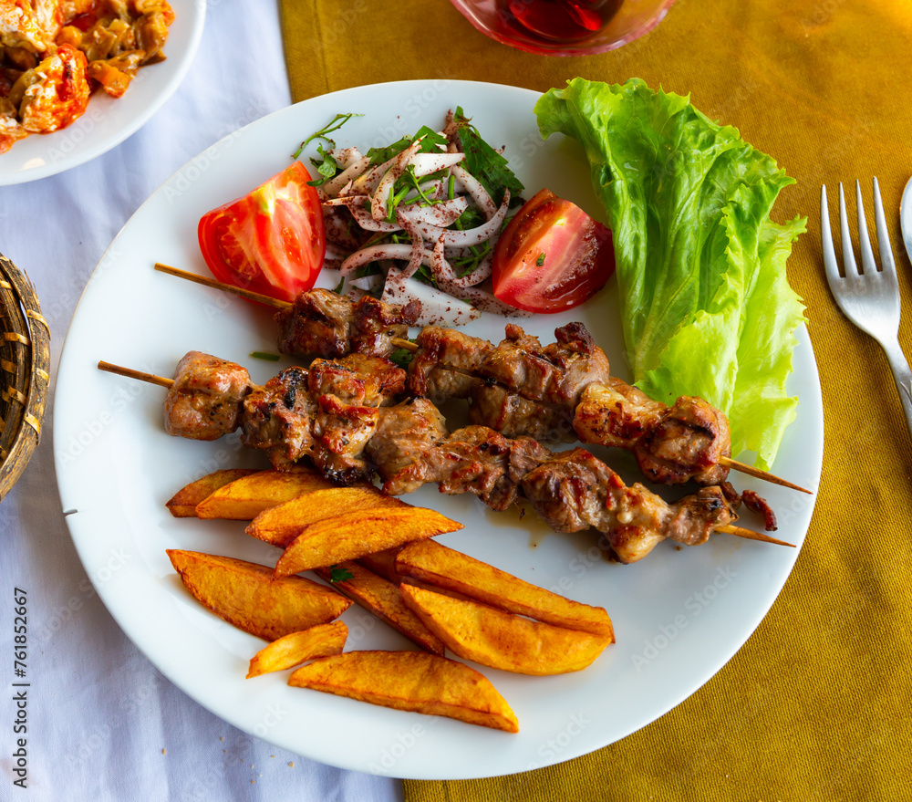 Lamb shish kebab with lettuce, tomatoes and French fries. Turkish cuisine