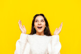 young shocked asian woman with braces wonders and holds empty hands over yellow isolated background, korean girl raises her hands up in amazement