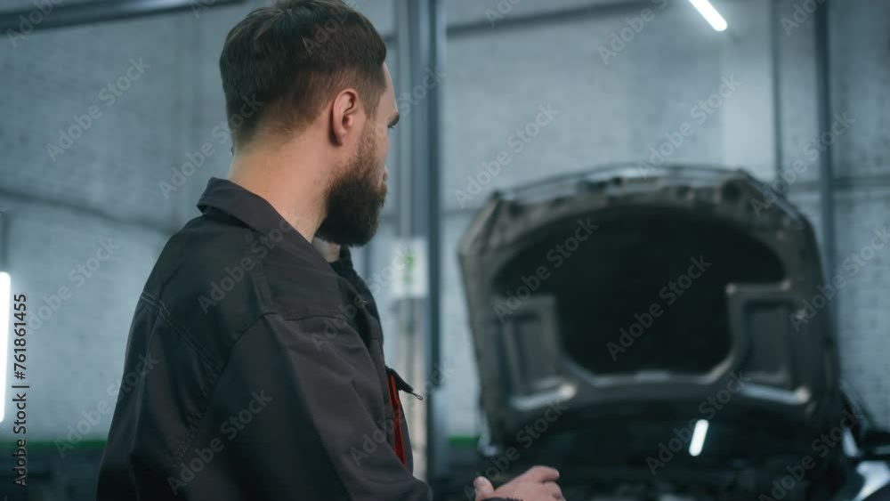 Caucasian man male guy mechanic in car service station industrial worker in uniform talking phone smartphone conversation answer mobile call talk with client explain automobile problem order details Caucasian man male guy mechanic in car service station industrial worker in uniform talking phone smartphone conversation answer mobile call talk with client explain automobile problem order details