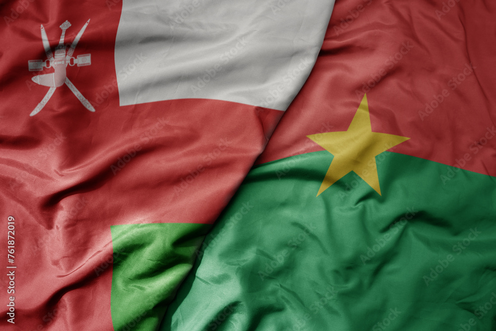 big waving national colorful flag of burkina faso and national flag of oman. big waving national colorful flag of burkina faso and national flag of oman.