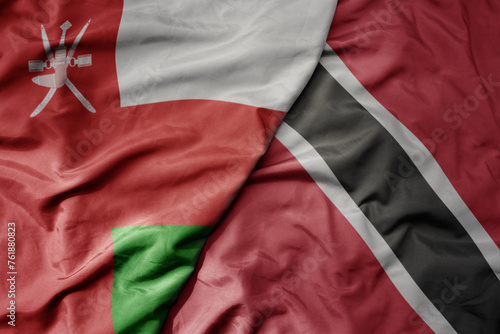 big waving national colorful flag of trinidad and tobago and national flag of oman.