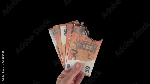 Female hand holding euro banknotes while burning. Green screen, isolated on black background with alpha channel. The concept of inflation and devolution, the depreciation of money, the global crisis.